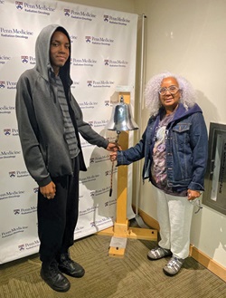 Charlene Heard, left, and her son, Myles, ring the bell at the Abramson Cancer Center.